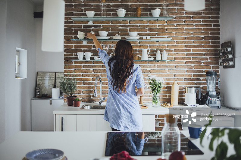 在厨房里伸手拿盘子的白人女性图片素材