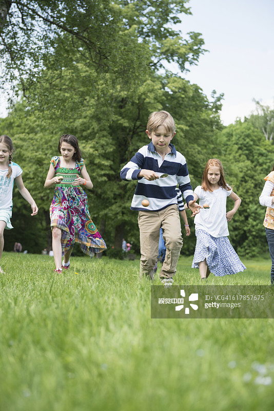 在德国巴伐利亚慕尼黑公园里参加鸡蛋竞走比赛的儿童图片素材