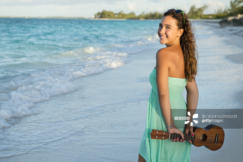 在海滩上拿着尤克里里的西班牙裔少女图片素材