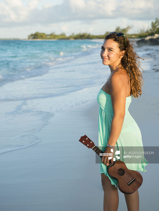 在海滩上拿着尤克里里的西班牙裔少女图片素材