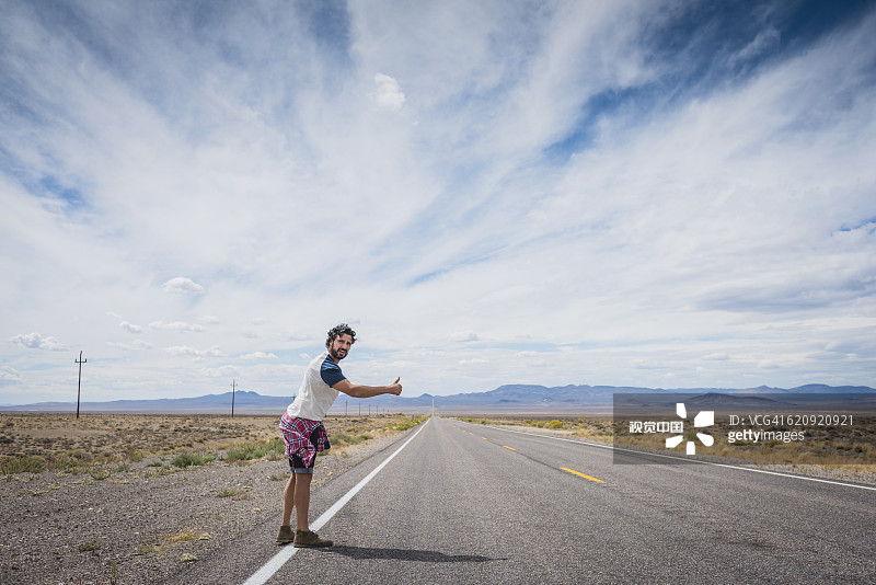 在偏远道路上搭便车的西班牙裔男人图片素材