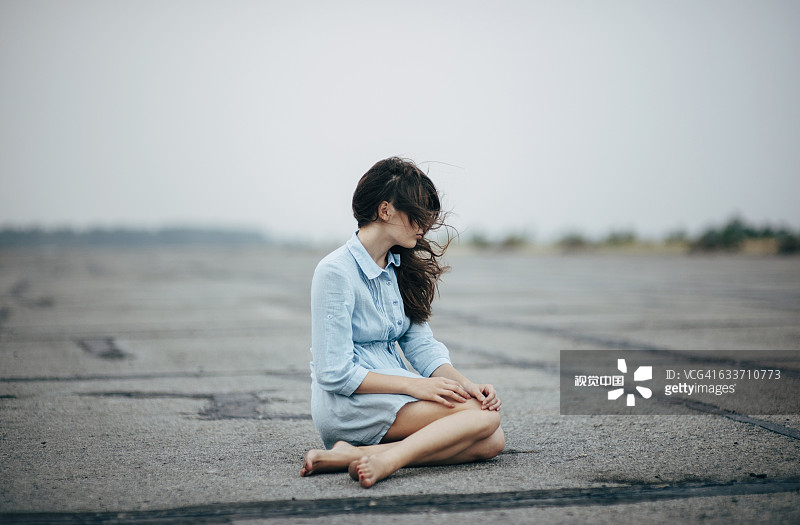 一个白人女人坐在水泥地上图片素材