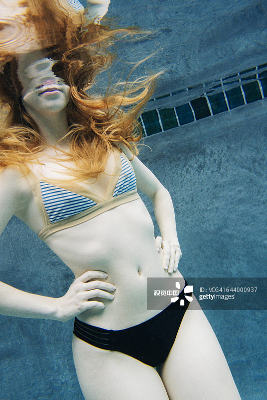 在游泳池里双手叉腰的白人女性图片素材