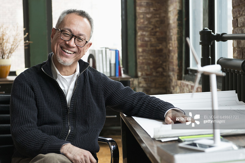 在办公室里拿着蓝图微笑的亚洲商人图片素材