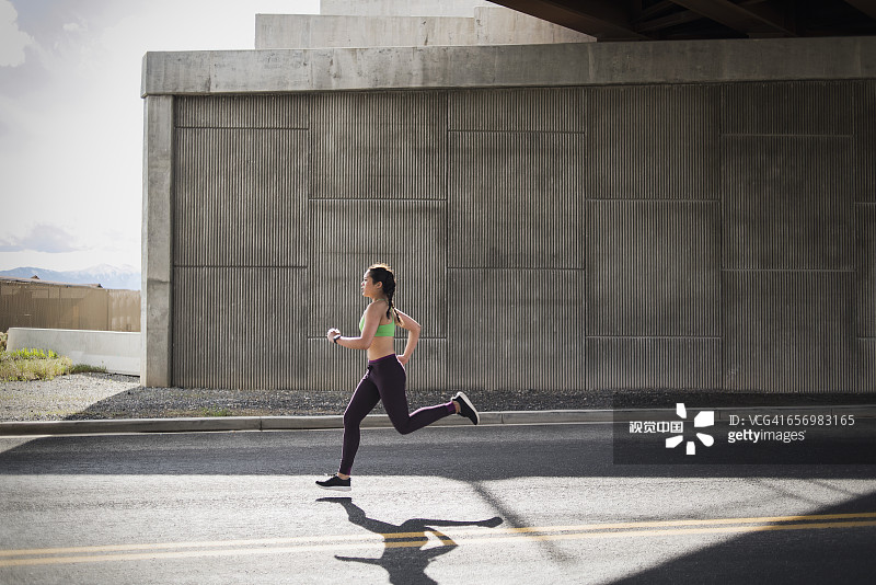 年轻女子在高速公路立交桥下奔跑图片素材