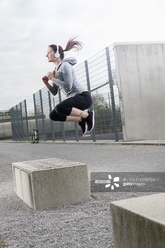 年轻女子在德国巴伐利亚的混凝土块上跳跃并听音乐图片素材