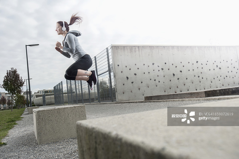 年轻女子在德国巴伐利亚的混凝土块上跳跃并听音乐图片素材