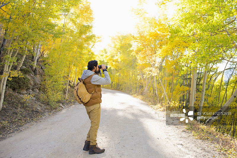 在徒步小路上用双筒望远镜观察的西班牙裔男人图片素材