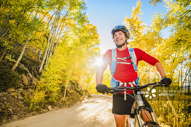 白人男子在森林小路上休息，身旁是山地自行车图片素材