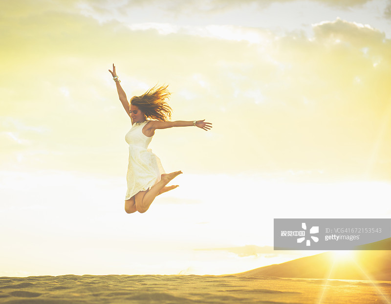 拉丁裔女人在沙丘上喜悦地跳跃图片素材
