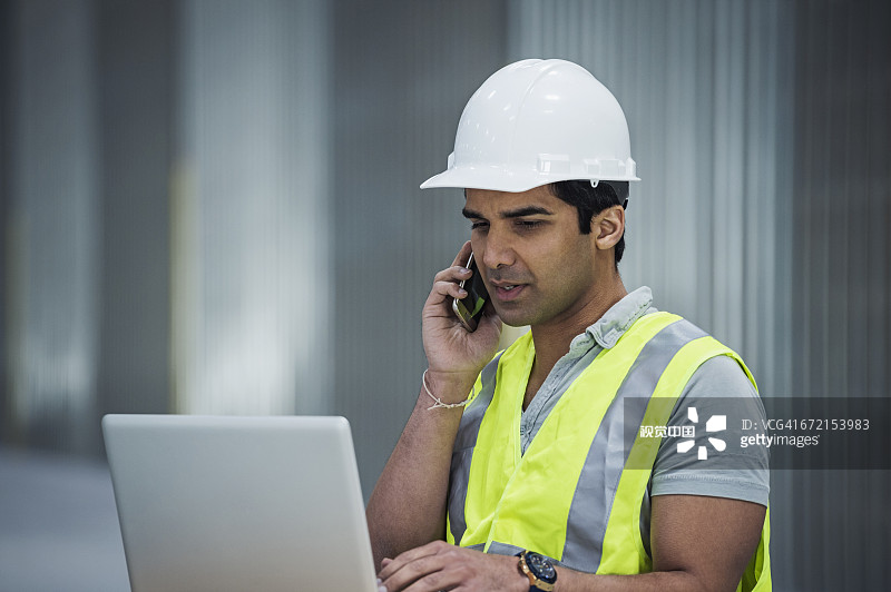 印度工人在仓库使用笔记本电脑和手机图片素材