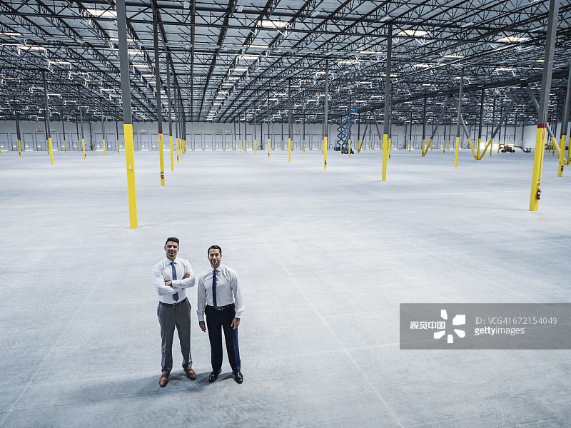 在空旷仓库中摆姿势的微笑商人图片素材