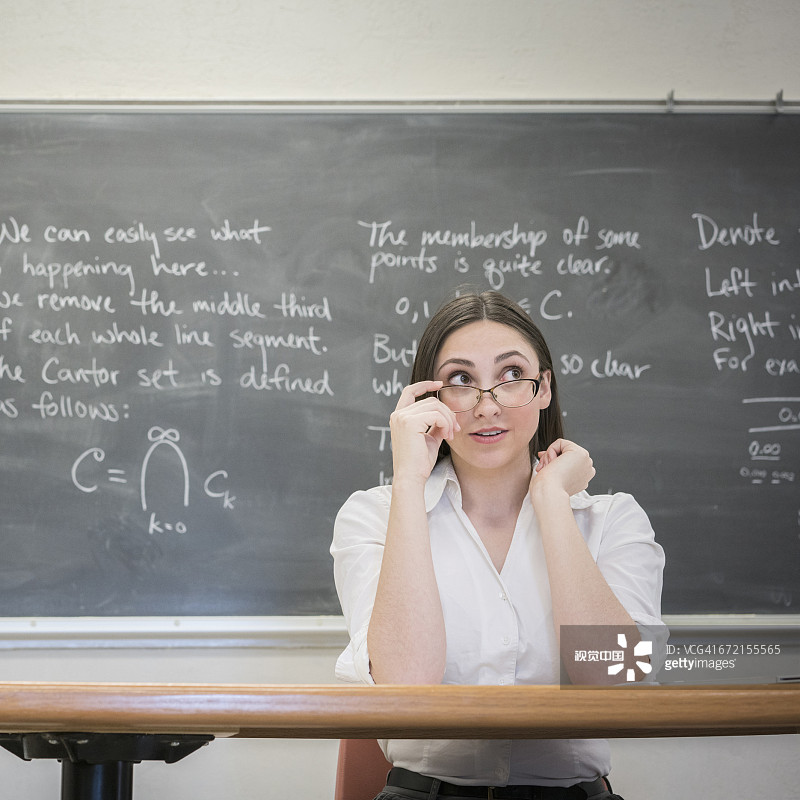 白人妇女在教室的桌子上放下眼镜图片素材