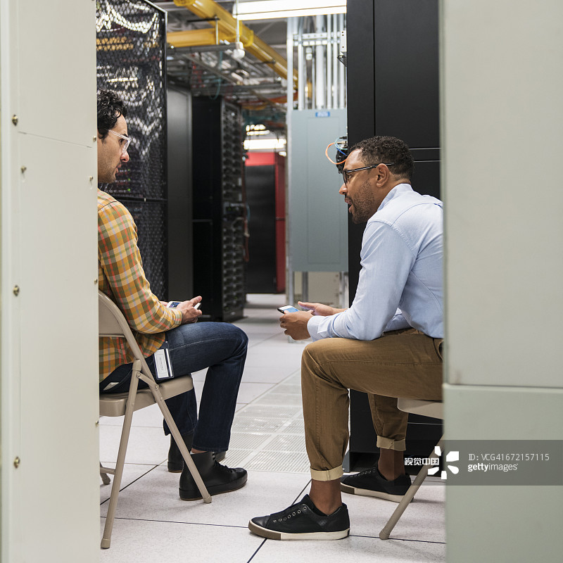 技术员在计算机服务器机房用手机发短信图片素材