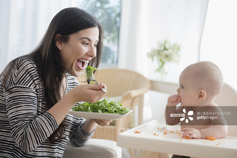 白人女性在照顾女儿的同时吃沙拉图片素材
