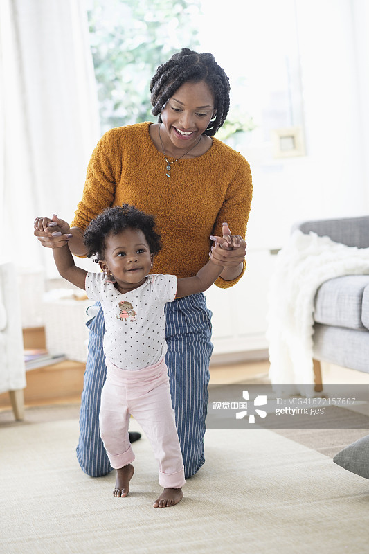 黑人母亲帮助女儿学习走路图片素材