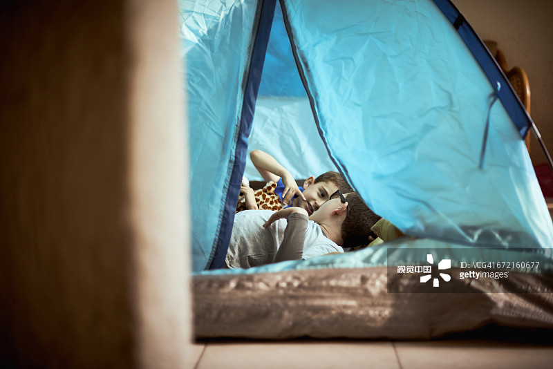 西班牙裔男孩在室内帐篷里露营图片素材
