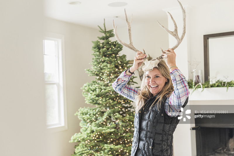 在圣诞树附近头戴鹿角的白人妇女图片素材