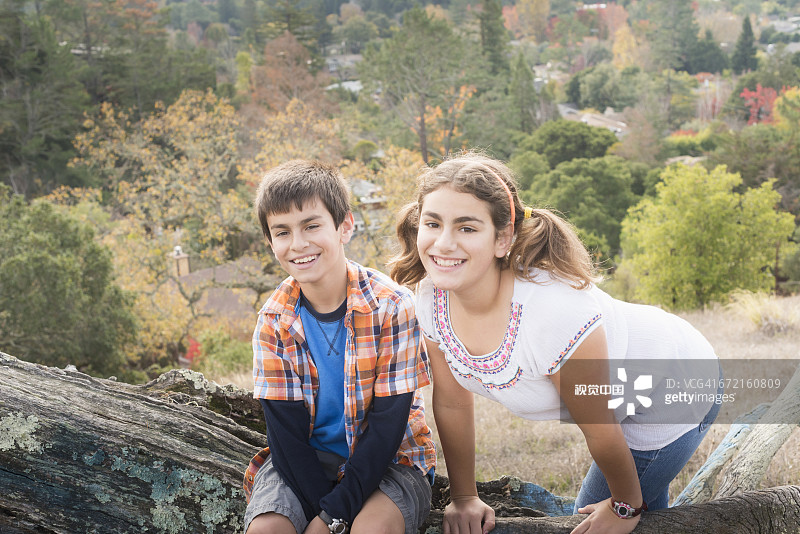 在原木上摆姿势的混血兄妹图片素材