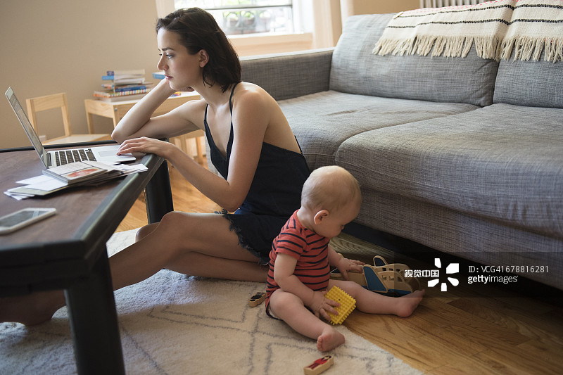 白人母亲坐在地板上，在儿子附近使用笔记本电脑图片素材