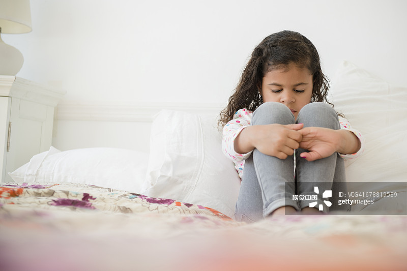 不快乐的混血女孩坐在床上图片素材