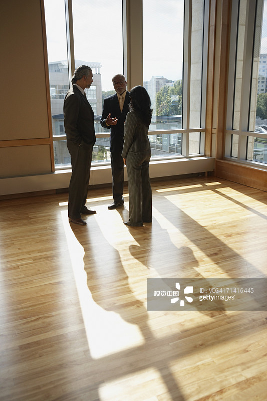 三个商人在阳光明媚的房间里交谈图片素材