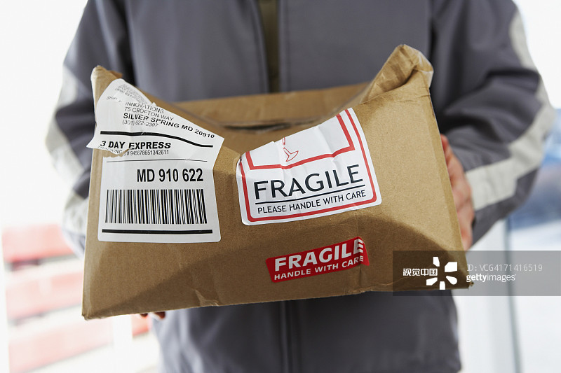 男子拿着压碎的标有“易碎品”的包裹图片素材
