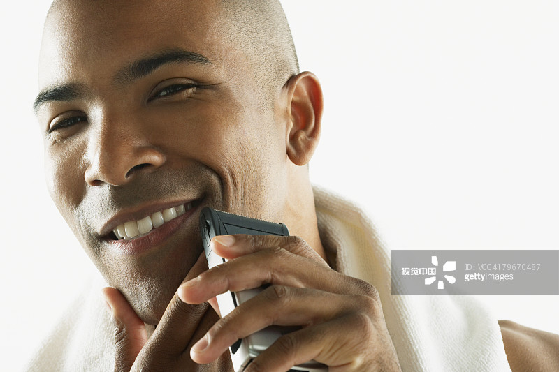 非裔美国男子用电动剃须刀刮脸图片素材