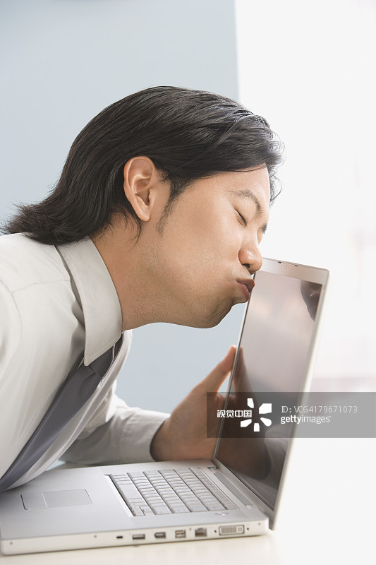 亚洲商人亲吻笔记本电脑图片素材