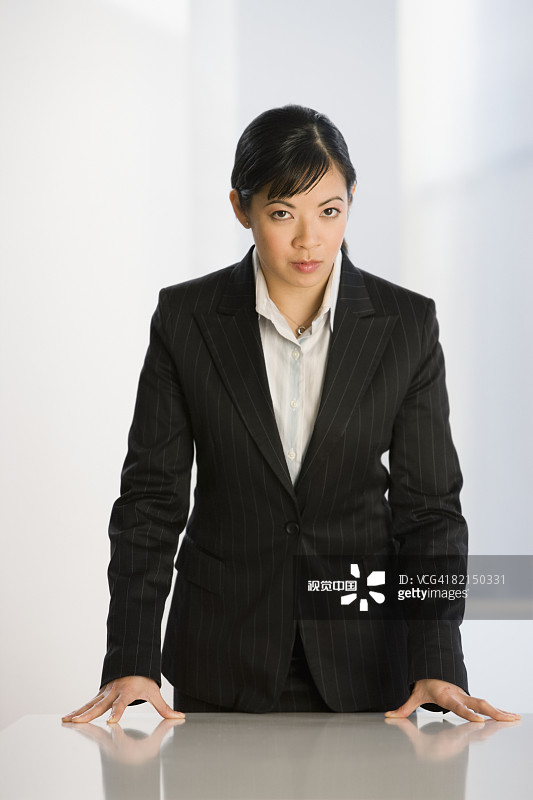 靠在桌子上的亚洲女商人图片素材