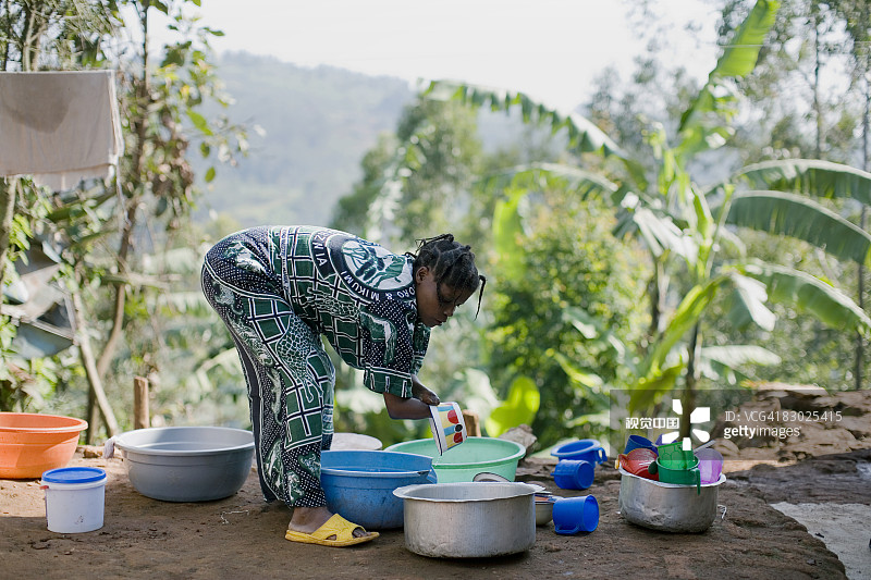 截肢妇女在布卡武的房子外面洗碗图片素材