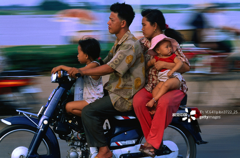 年轻家庭骑摩托车，柬埔寨金边图片素材