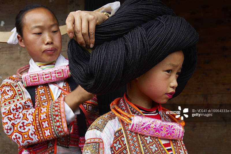 中国贵州：妇女帮助女孩（8-9岁）穿传统服饰图片素材