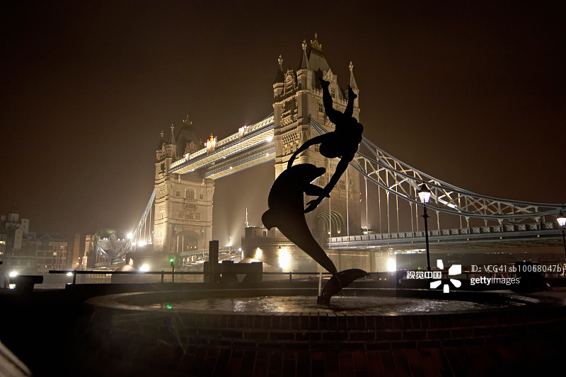 英国伦敦：夜幕下的塔桥剪影与女孩海豚雕像图片素材