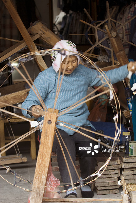 中国周庄，妇女在木制纺车上纺羊毛，面带微笑图片素材